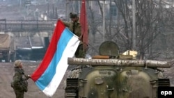 Russian soldiers unfold their flag in Grozny in 2000 