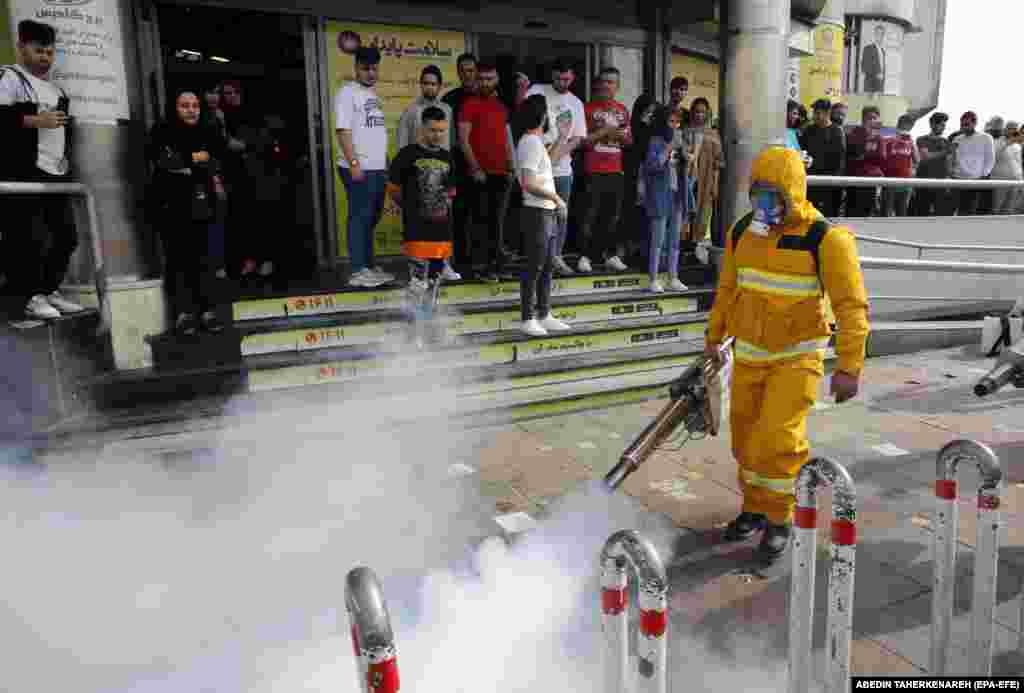 Iranians take pictures of firefighters as they disinfect streets in Tehran.