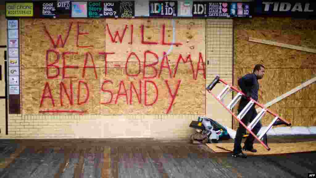 Raymond Souza carries away a ladder after boarding up Tidal Rave's 5 & 10 gift shop on the boardwalk ahead of Hurricane Sandy's landfall in Rehoboth Beach, Delaware. 