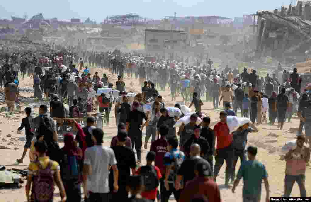 Palestinienii care își transportă sacii cu făină primiți de la organizațiile umanitare. Beit Lahia, în nordul Fâșiei Gaza, 20 iulie 2025.Un raport al ONU arată că peste 1.000 de palestinieni au fost uciși de forțele israeliene începând din mai, în timp ce încercau să obțină hrană, în special în apropierea punctelor de distribuție gestionate de Fundația Umanitară Gaza (GHF), susținută de Israel și SUA.