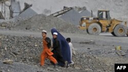 An Afghan woman and her children walk near an open-cast mine in the Turkham Nangarhar region of Afghanistan bordering Pakistan. Manufacturing, mining, and Afghanistan's agricultural sectors would be the most likely areas of investment. 