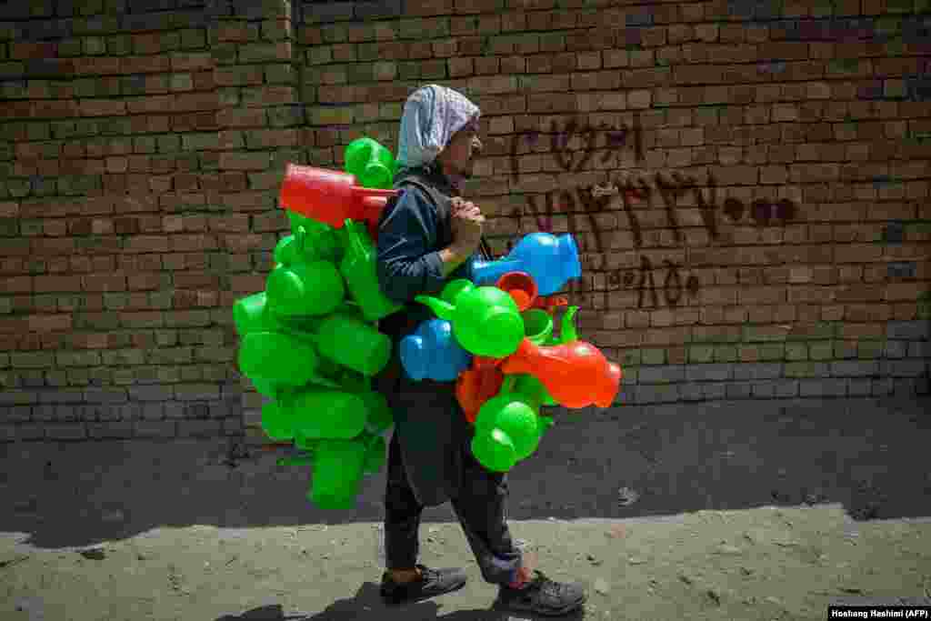 Sokolar koji prodaje plastične kanistere šeta jednom ulicom na pijaci u Kabulu, Afganistan.