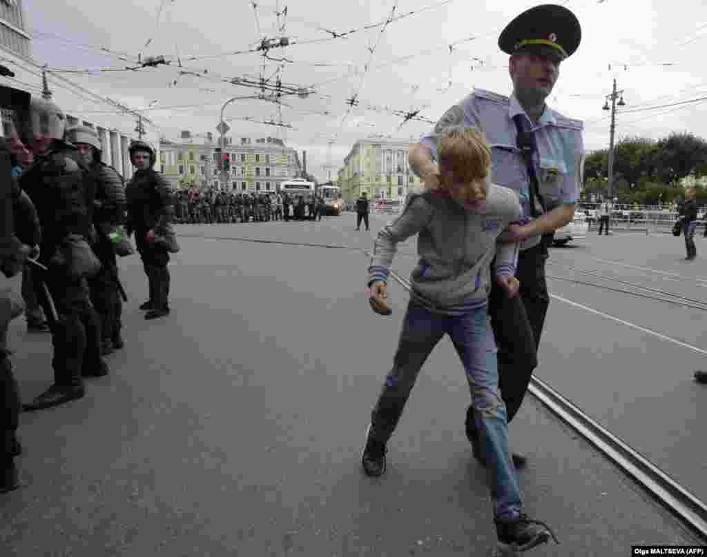 A child is led away by a police officer during a protest in St. Petersburg. 