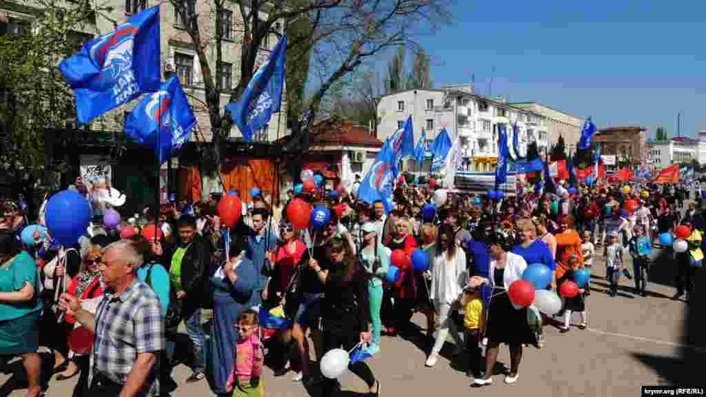 На первомайскую демонстрацию многие керчане взяли с собой детей. Люди несут в руках флаги, цветы, воздушные шары. 