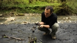 Suren Gazarian examines a black substance that he said was part of a mudslide emanating from an illegal dump, close to the 2014 Olympics construction outside the Black Sea resort of Sochi in April 2011.