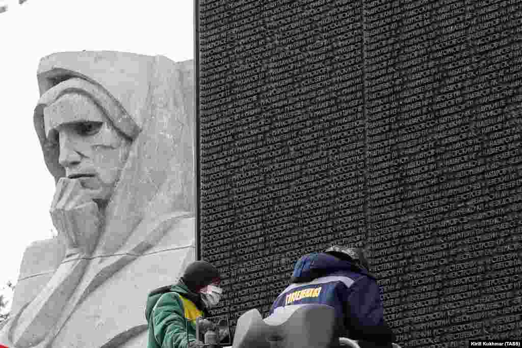 Workers clean the names of World War II soldiers at the Glory Monument in Novosibirsk on April 13, 2020. 