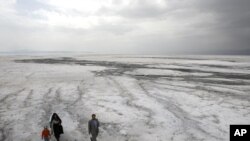 A family walks on the solidified salts of Lake Orumieh.